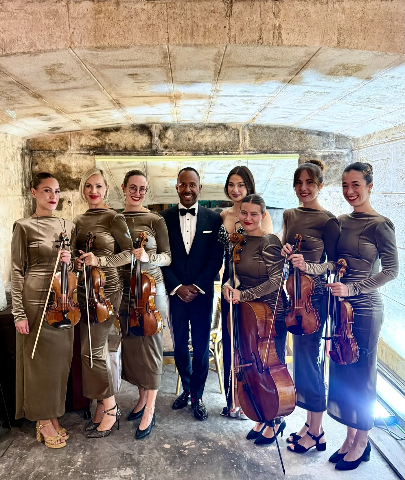 Inan Lima im Smoking mit Sängerin und sechsköpfigem Streichensemble mit Violinen und Cello vor einem Steingewölbe auf Mallorca